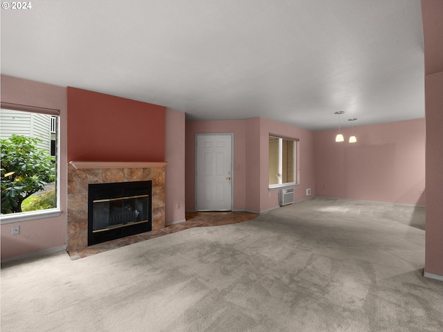 unfurnished living room featuring a fireplace, an AC wall unit, baseboards, and carpet floors