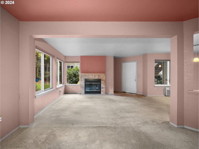 unfurnished living room featuring light colored carpet, a high end fireplace, and an AC wall unit