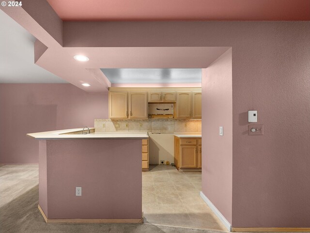 kitchen with light brown cabinets, light colored carpet, kitchen peninsula, and decorative backsplash