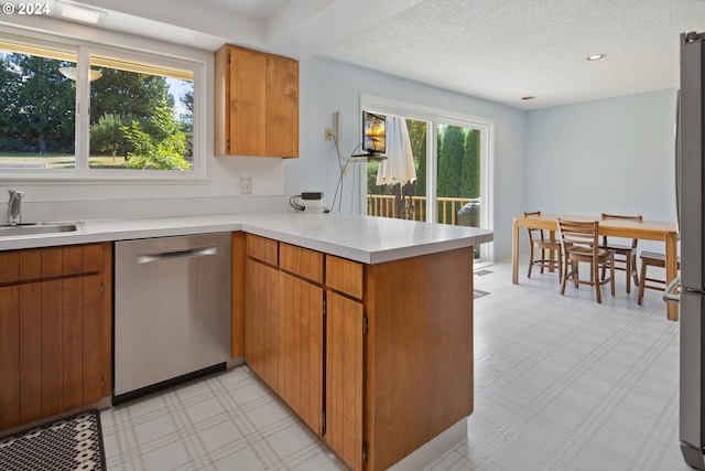 kitchen featuring sink, kitchen peninsula, a textured ceiling, and stainless steel dishwasher