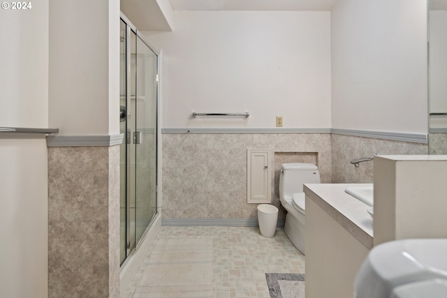 bathroom with tile walls, vanity, toilet, and a shower with shower door