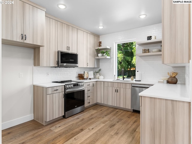 kitchen with light brown cabinetry, sink, backsplash, light wood-type flooring, and stainless steel appliances