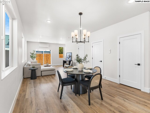 dining space with light hardwood / wood-style floors, an AC wall unit, and a chandelier