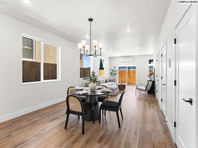 dining area featuring a wall mounted air conditioner, an inviting chandelier, and wood-type flooring