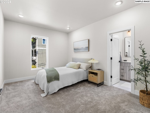 bedroom with light carpet and connected bathroom