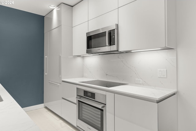 kitchen with white cabinetry, light stone counters, appliances with stainless steel finishes, and tasteful backsplash