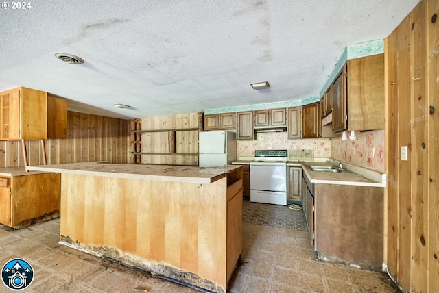 kitchen with sink, white appliances, a center island, and wooden walls