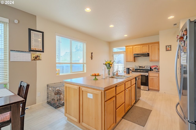 kitchen featuring appliances with stainless steel finishes, light brown cabinets, sink, and an island with sink