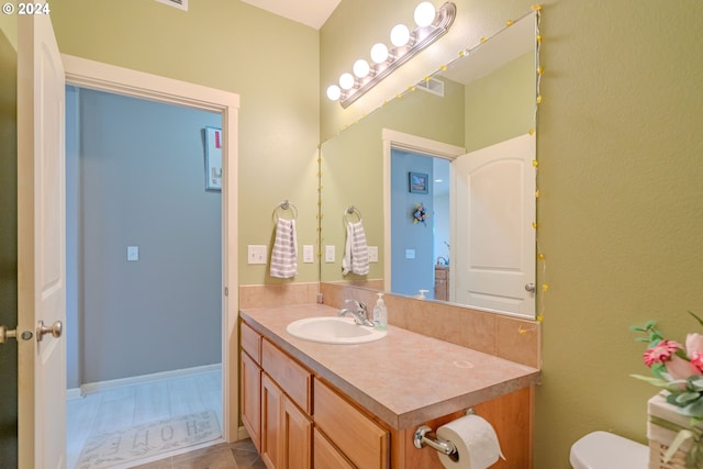 bathroom with toilet, vanity, and tile patterned flooring