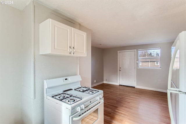 kitchen with hardwood / wood-style floors, white appliances, and white cabinets