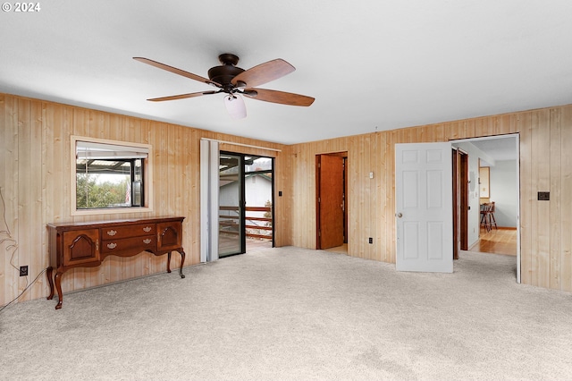 bedroom with ceiling fan, carpet floors, wooden walls, and access to exterior