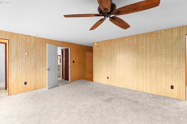 spare room featuring carpet, ceiling fan, and wooden walls