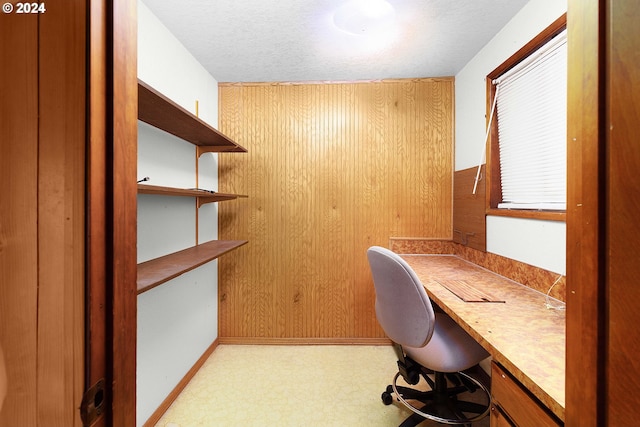 unfurnished office featuring wood walls and a textured ceiling