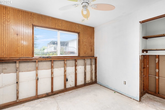 empty room featuring wooden walls and ceiling fan