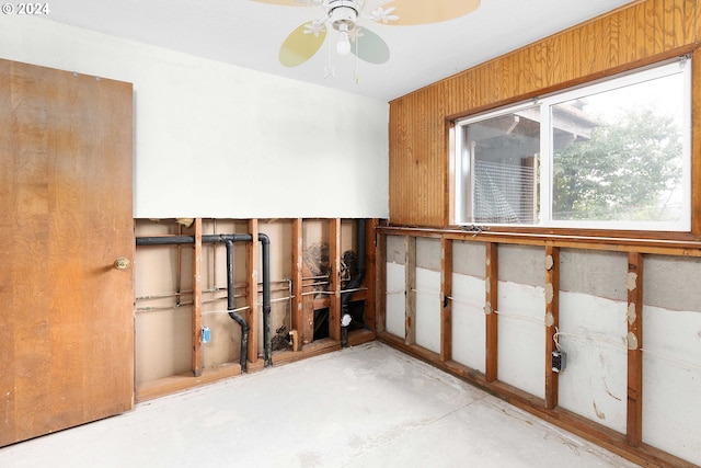 spare room with ceiling fan and wood walls