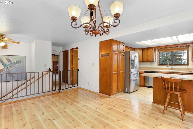 kitchen featuring appliances with stainless steel finishes, light hardwood / wood-style flooring, decorative light fixtures, and sink