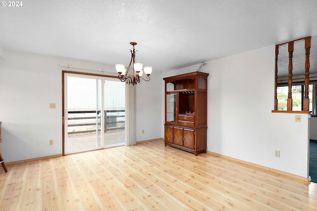 interior space with a notable chandelier, a textured ceiling, and light wood-type flooring