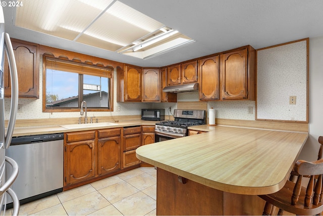 kitchen with light tile patterned floors, stainless steel appliances, sink, and kitchen peninsula