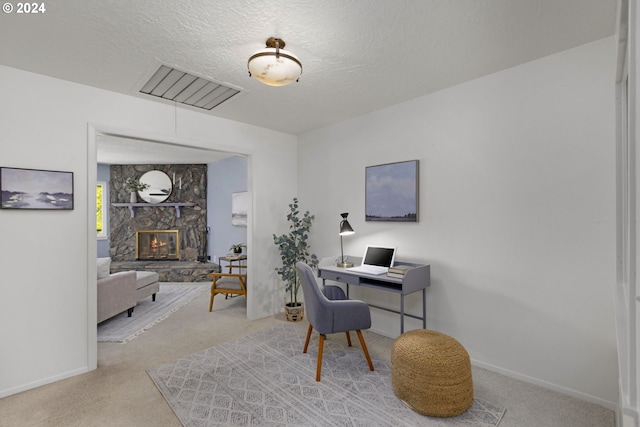 office with carpet flooring, a fireplace, and a textured ceiling