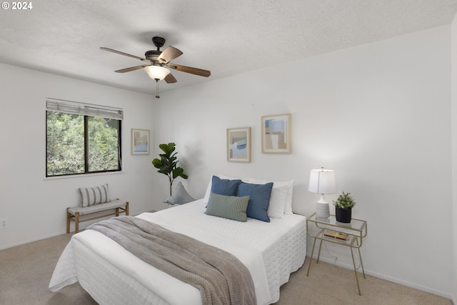 bedroom featuring a textured ceiling, ceiling fan, and light carpet