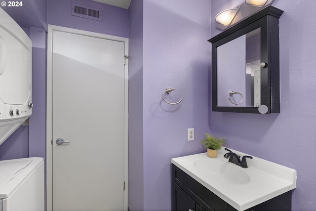 bathroom featuring stacked washer and dryer and vanity