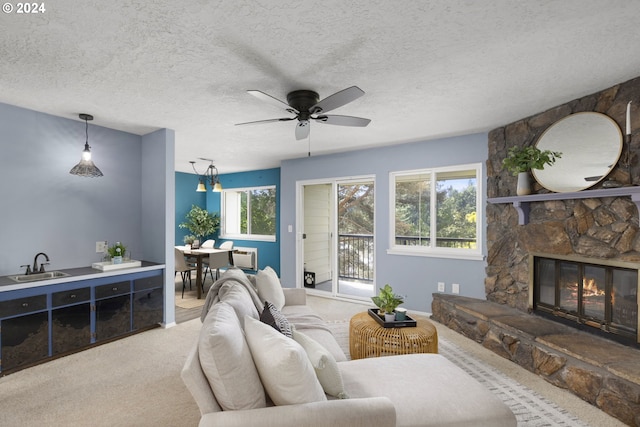 carpeted living room with a fireplace, ceiling fan, a healthy amount of sunlight, and sink