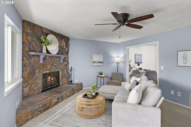 carpeted living room featuring a fireplace, a textured ceiling, and ceiling fan