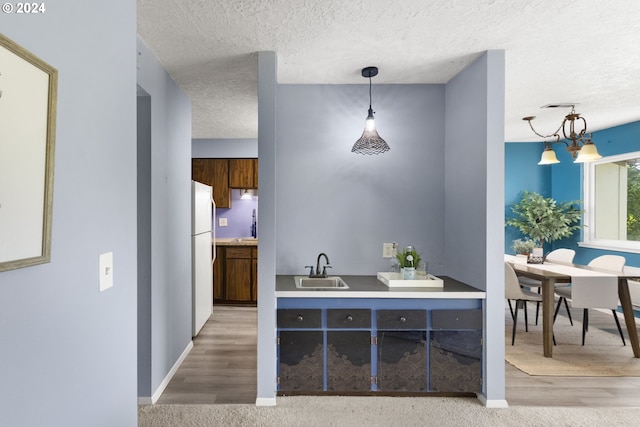 bar featuring sink, light hardwood / wood-style flooring, pendant lighting, a chandelier, and a textured ceiling