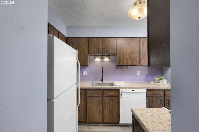 kitchen featuring dark brown cabinets, white appliances, and a textured ceiling