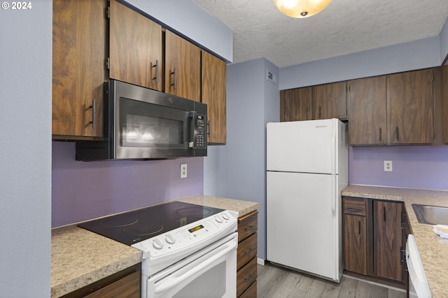 kitchen with light hardwood / wood-style floors, sink, white appliances, and a textured ceiling