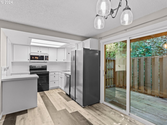 kitchen featuring white cabinetry, hanging light fixtures, stainless steel appliances, and light wood-type flooring