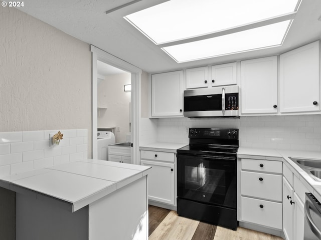 kitchen featuring kitchen peninsula, light wood-type flooring, backsplash, stainless steel appliances, and white cabinets