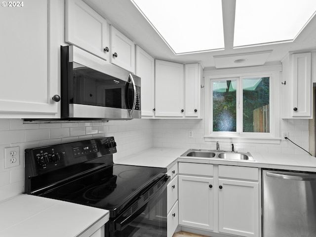 kitchen with white cabinets, stainless steel appliances, tasteful backsplash, and sink