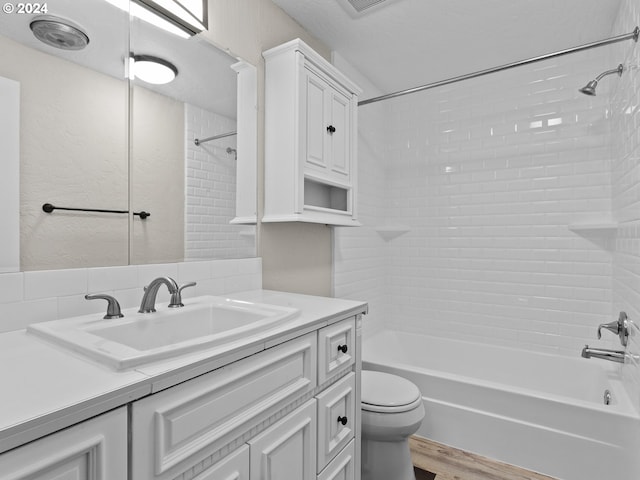 full bathroom with tiled shower / bath, hardwood / wood-style floors, vanity, and toilet