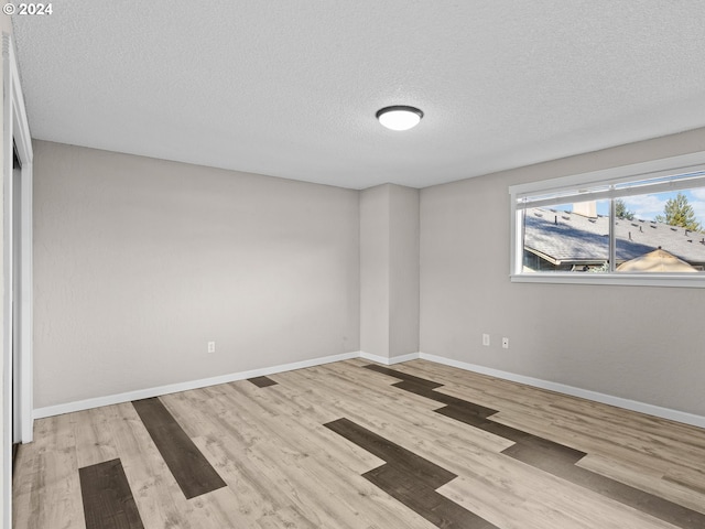 empty room featuring a textured ceiling and light wood-type flooring