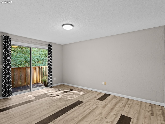 unfurnished room with light wood-type flooring and a textured ceiling