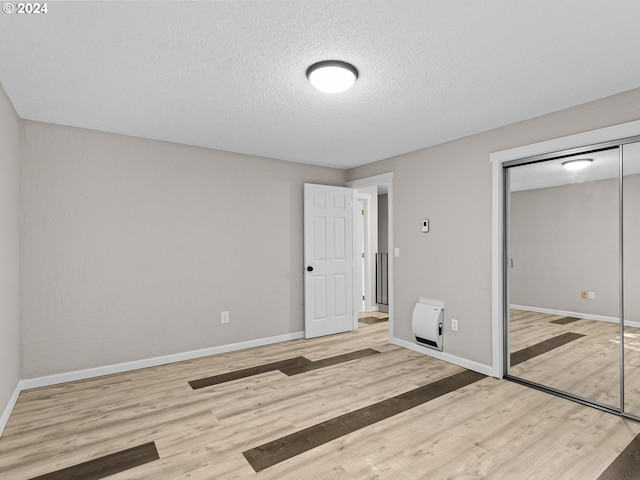 unfurnished bedroom featuring a textured ceiling, light hardwood / wood-style flooring, and a closet