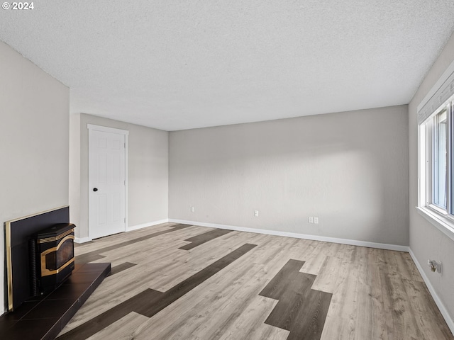 unfurnished living room with a wood stove, wood-type flooring, and a textured ceiling