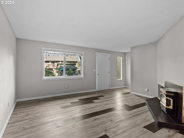 living room featuring light hardwood / wood-style floors, a wood stove, and a healthy amount of sunlight