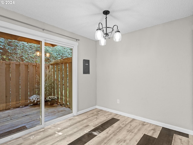 unfurnished dining area with hardwood / wood-style floors, a textured ceiling, and a notable chandelier