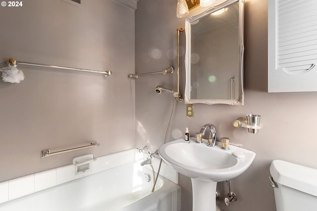 bathroom with sink, toilet, and a tub to relax in