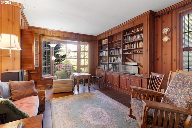 living area featuring built in shelves, a wealth of natural light, wood walls, and dark hardwood / wood-style floors