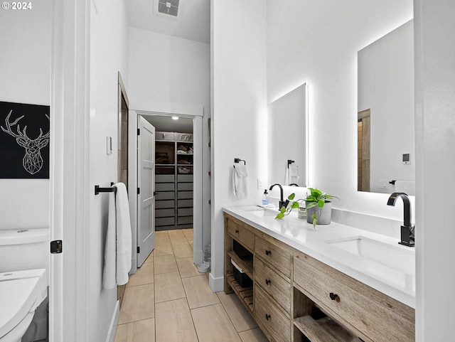 full bath featuring a sink, visible vents, toilet, and a walk in closet