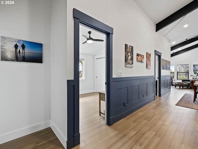 hall featuring a decorative wall, wainscoting, vaulted ceiling with beams, and wood finished floors
