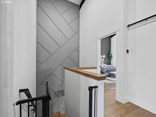 staircase featuring visible vents, baseboards, a barn door, and wood finished floors