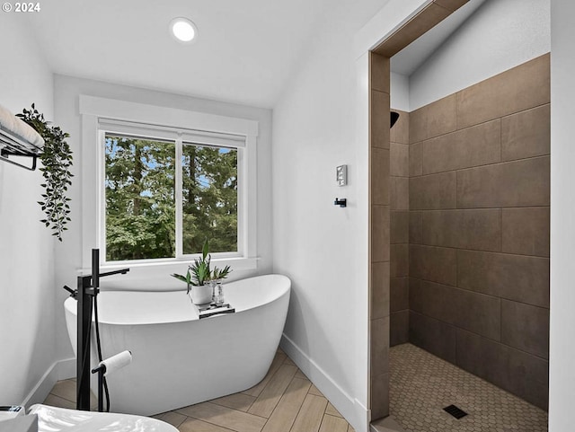 bathroom featuring a freestanding tub, baseboards, and tiled shower
