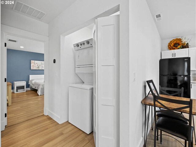 kitchen with black appliances, light stone countertops, light wood-type flooring, white cabinets, and sink