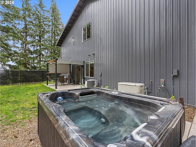 wooden terrace with a hot tub, a patio, a yard, and central AC