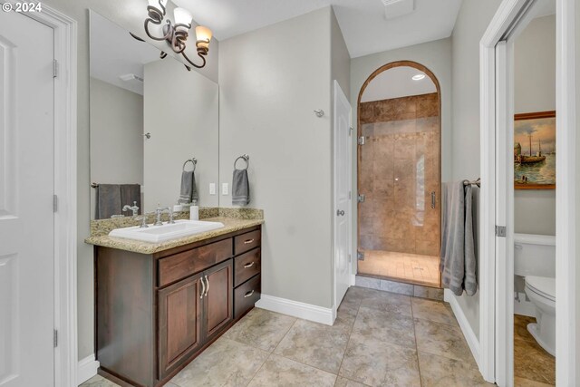 bathroom with tiled shower, vanity, toilet, a chandelier, and tile patterned floors