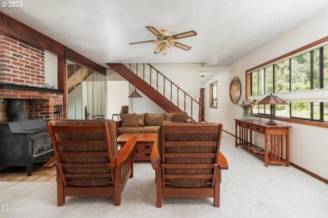 carpeted living room featuring a ceiling fan, stairway, a wood stove, and baseboards